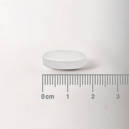 White pill with a ruler for scale on a white background