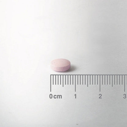 Pink pill on a white background with a ruler for scale.