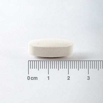 White pill with a ruler for scale on a white background